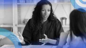 Internal recruiting image of a woman talking and gesturing to another person across a table. 