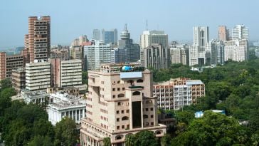 An aerial view of New Delhi featuring several skyscrapers surrounded by trees.